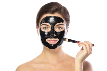 Beautiful woman is applying purifying black mask on her face