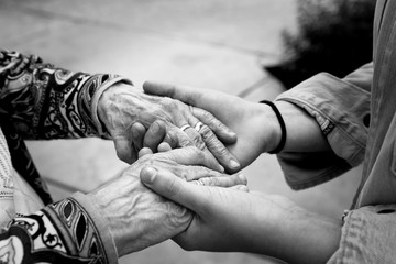 Young hands supporting old hands-helping elderly people concept-black and white image with...