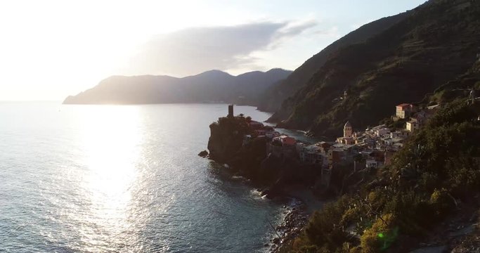 aerial view of travel landmark destination Vernazza, a small mediterranean sea town, Cinque terre National Park, Liguria, Italy. Sunset with cloud and flare. 4k aerial drone side video shot
