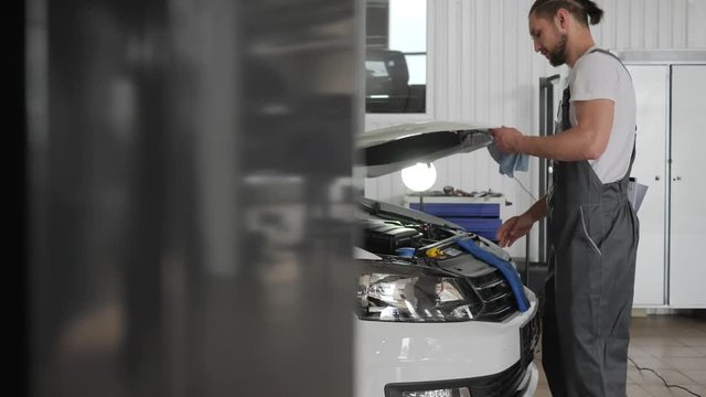 cute mechanic working in machine repair shop, master engine review, automobile service, male inspection technical condition car, professional auto, mechanician looks motor auto, maintenance,