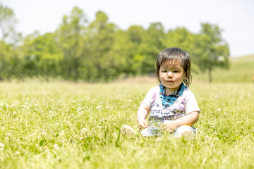 牧草地に1人座る男児赤ちゃん