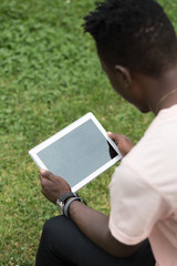 African american male hands holding tablet pc on grass background