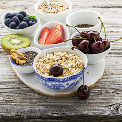 Ingredients for a healthy breakfast, nuts, oatmeal, honey, berries, fruits, blueberry, orange, pomegranate seeds, almonds, walnuts The concept of natural organic food in season Top view