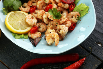 fresh shrimps served on a plate with garlic onion, lemon and chili
