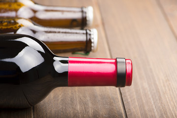 Close-up of a bottle of wine and two bottles of beer on the wooden background. Copy space. Horizontal shoot.