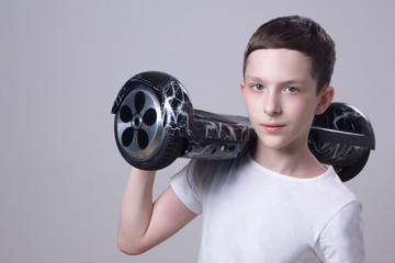 Fototapeta premium Caucasian guy in a white T-shirt holds on his right shoulder a super popular black color with a lightning hoverboard.