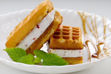 Viennese waffles with souffle,strawberry pieces,caramel and mint on a white plate