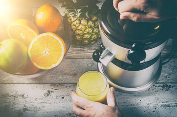 Man preparing fresh orange juice. Fruits in background
