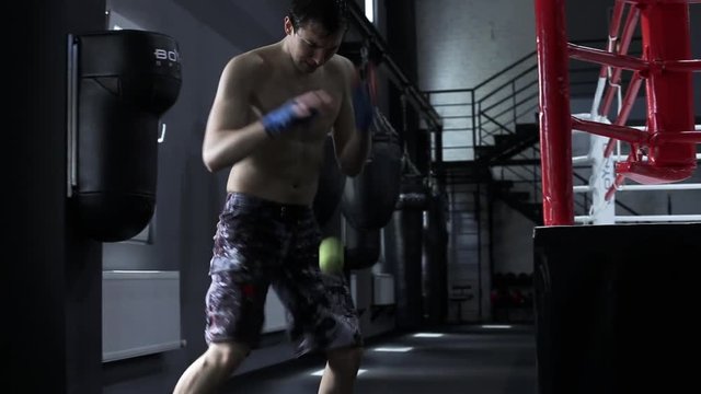 Professional sportsman male boxer trains speed and coordination with a tennis ball.