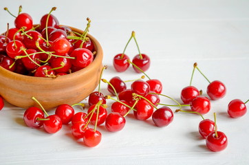 Obraz na płótnie Canvas Brown ceramic bowl of fresh and tasty cherries on wooden white background
