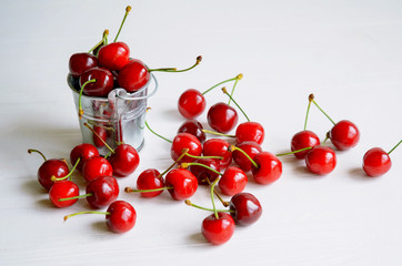 Obraz na płótnie Canvas Ripe sweet cherries in a little tin bucket on white wooden background, tasty and healthy dessert