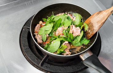 Fry pork with basil in frying pan. Pad Ka prao (Stir Fried Pork with Holy Basil). Cooking fried chilly paste with pork.