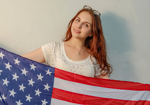 Young woman with american flag in hands looking at camera vintage colored image