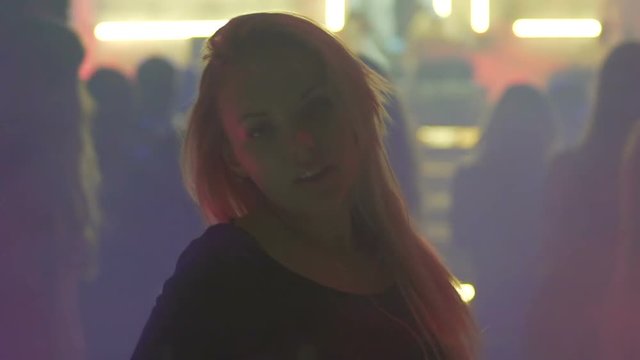 Beautiful blonde lady dancing, playing hair and flirting with someone at concert