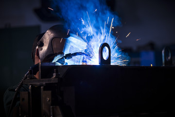 Young industrial worker welding in the factory
