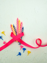 striped colorful candles with pink ribbon for birthday party on white background. flat lay.