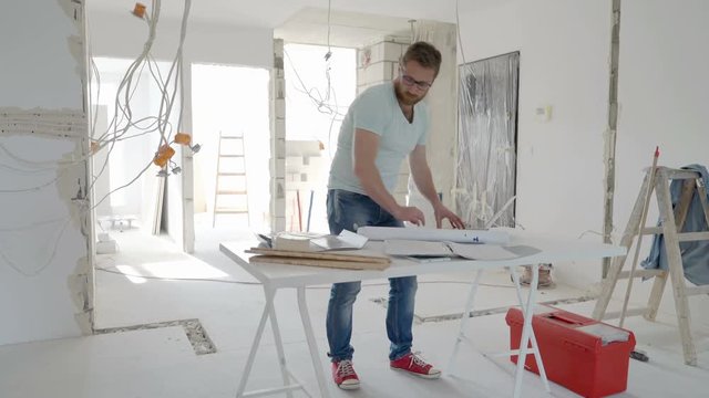 Man standing in his new flat and checking documents about renovation, steadycam shot
