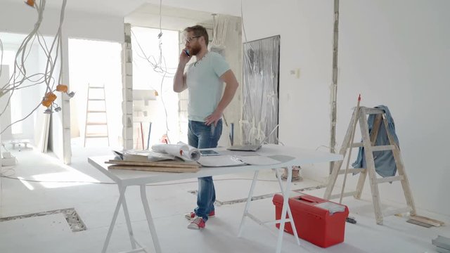 Architect standing in the new flat and talking on cellphone, steadycam shot
