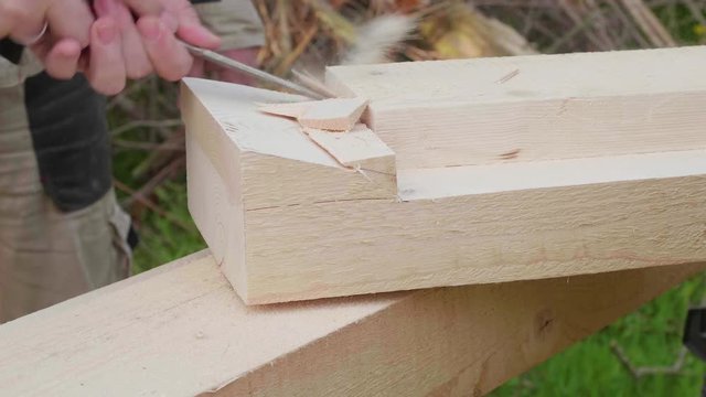 White carpenter works with hand chisel.
