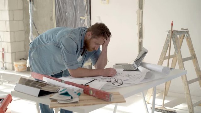 Man checking plans and looks irritated while having problems with it, steadycam shot
