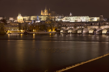 Night romantic snowy Prague gothic Castle and St. Nicholas' Cathedral with Charles Bridge, Czech republic