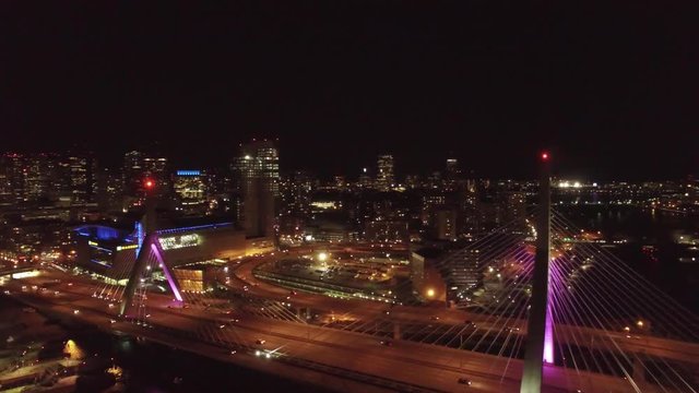 Sliding and backward flying aerial shot of famous landmark Zakim Bridge in Boston at night with traffic on the bridge