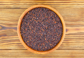Raw black rice in bowl on  wooden background