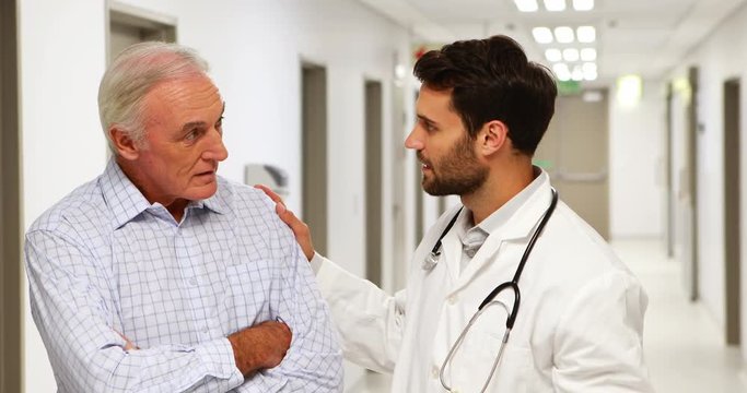 Doctor and patient discussing over clipboard in the corridor