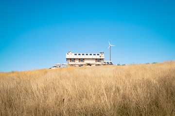 Fototapeta premium Alpine hut with photovoltaic panels and wind generator.