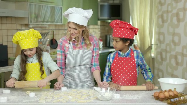 Smiling woman and children, kitchen. Kids make pastry.