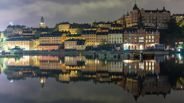 Stockholm city architecture buildings at night 4K Time Lapse. Sodermalm cityscape district, reflections in the water