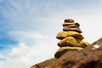 stacking of rock with blur sky and sea background