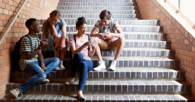Classmates African American boy sitting on staircase and using mobile phone