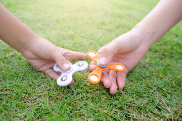 Boy holding play two fidget spinners, Fidget spinner white and ogange colour spinning stress...