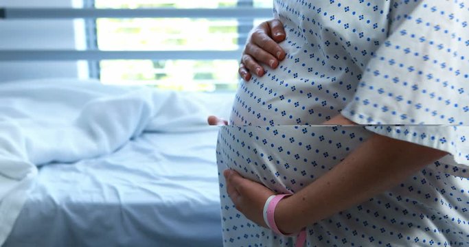 Pregnant woman touching her belly in ward