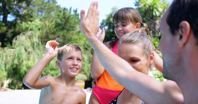 Happy family giving high five to each other near pool side