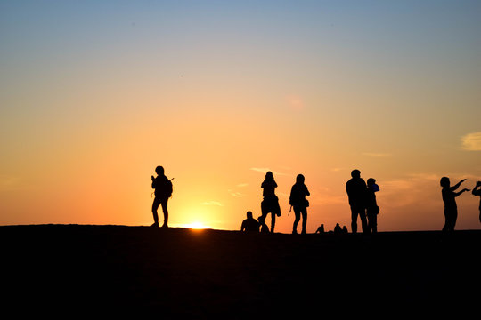 People in desert sunset 