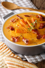 Delicious sweet potato cream soup with bacon and thyme close-up. vertical