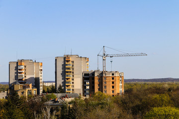 Building crane and building under construction against blue sky