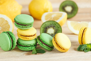 Green and yellow french macarons with kiwi, lemon and mint decorations