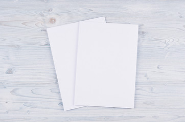 Blank white paper A4, envelope on soft light blue wooden board. Mock up for branding identity.