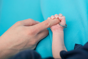 Newborn holding wedding ring.