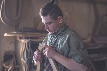 male carpenter working with a wood product, hand tools