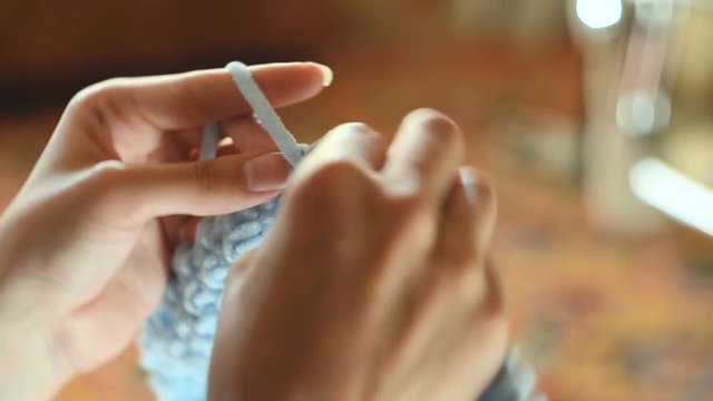 The concept of needlework - a young woman knits with circular knitting needles. Close-up
