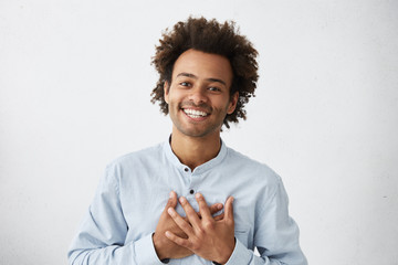 Lovely good-natured Afro American man in white shirt having charming smile and friendly expression...