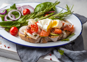 Egg poached and salmon on toast with vegetables. Egg benedict in rustic style.