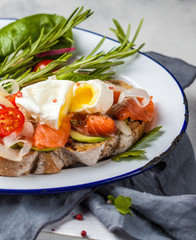 Egg poached and salmon on toast with vegetables. Egg benedict in rustic style.