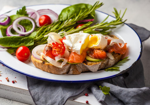 Egg poached and salmon on toast with vegetables. Egg benedict in rustic style.