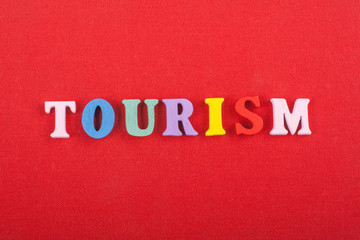 TOURISM word on red background composed from colorful abc alphabet block wooden letters, copy space for ad text. Learning english concept.