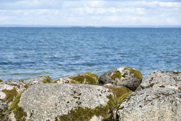 Fototapeta na wymiar Wall of big stone blocks and water. Nature background of beautiful scenic summer landscape.